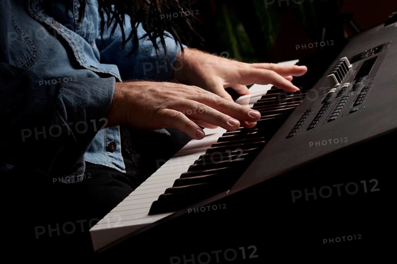 Male pianist performs on the piano keyboard with dramatic lighting