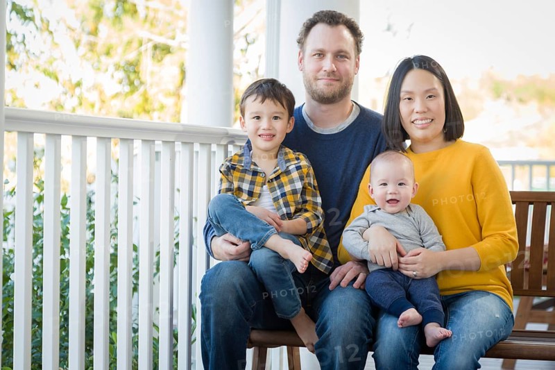 Young mixed-race chinese and caucasian family portrait on their front porch