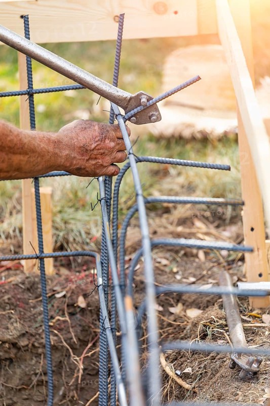 Worker using tools to bend steel rebar at construction site