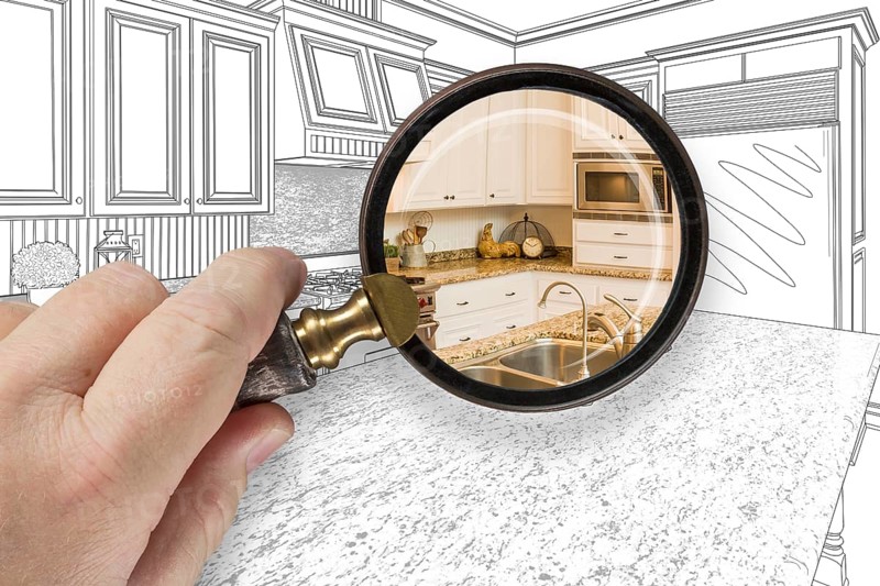 Hand holding magnifying glass revealing custom kitchen design drawing and photo combination