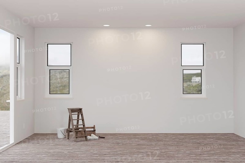 Ladder and painting equipment in raw unfinished room of house with blank white walls and worn wood floors