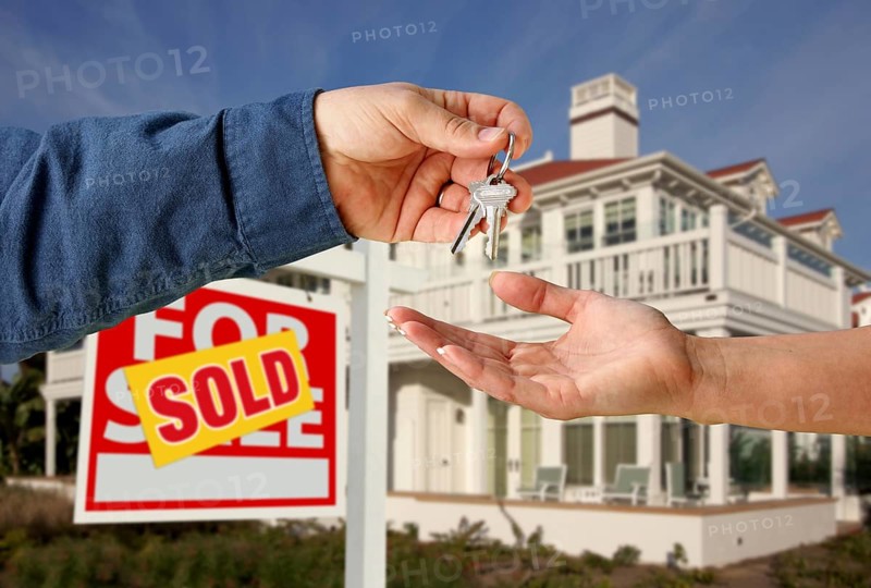 Handing over the house keys in front of a beautiful new home