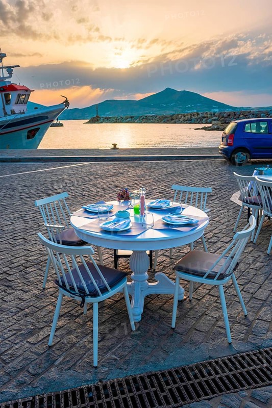 Street cafe table with ready for dinner on quay of Naousa town port in famous tourist attraction Paros island