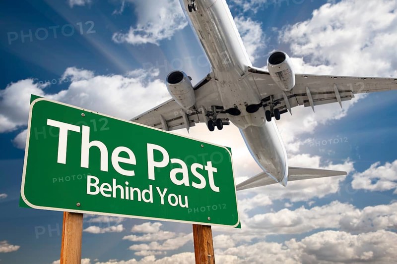 The past green road sign and airplane above with dramatic blue sky and clouds