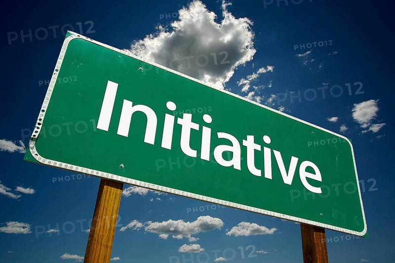 Initiative green road sign over dramatic clouds and sky