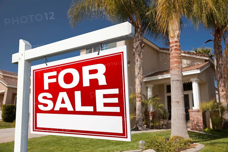 For sale real estate sign in front of house