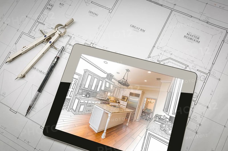 Computer tablet showing kitchen illustration sitting on house plans with pencil and compass