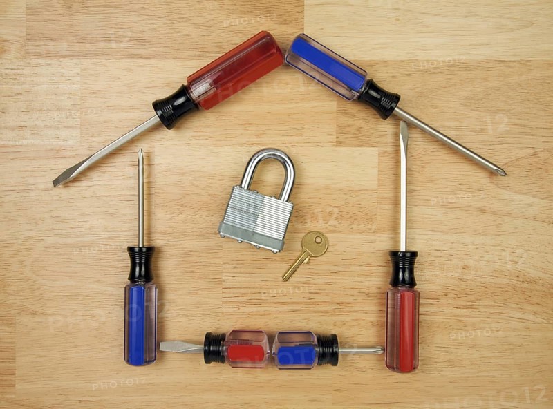 House shaped by screwdrivers with lock and key on a wood background