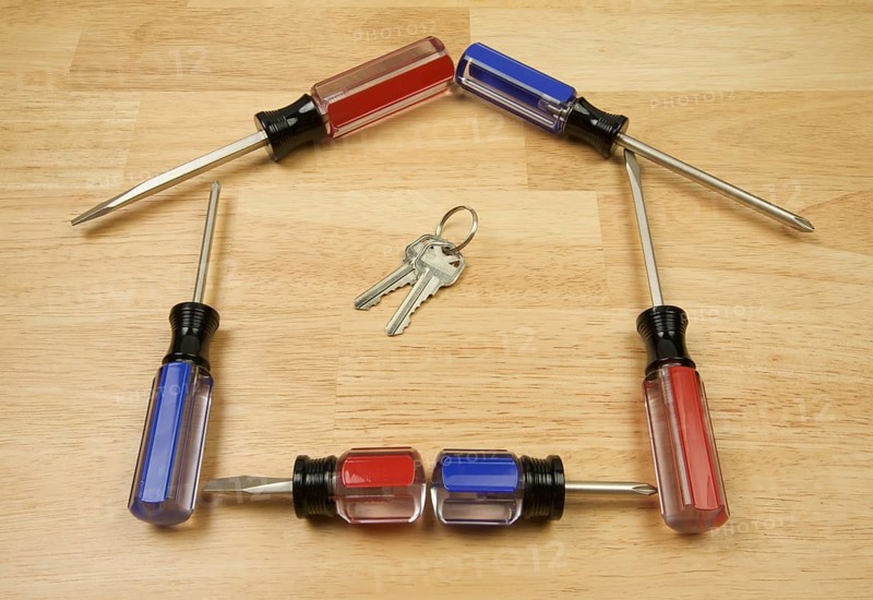 House shaped by screwdrivers and keys on a wood background