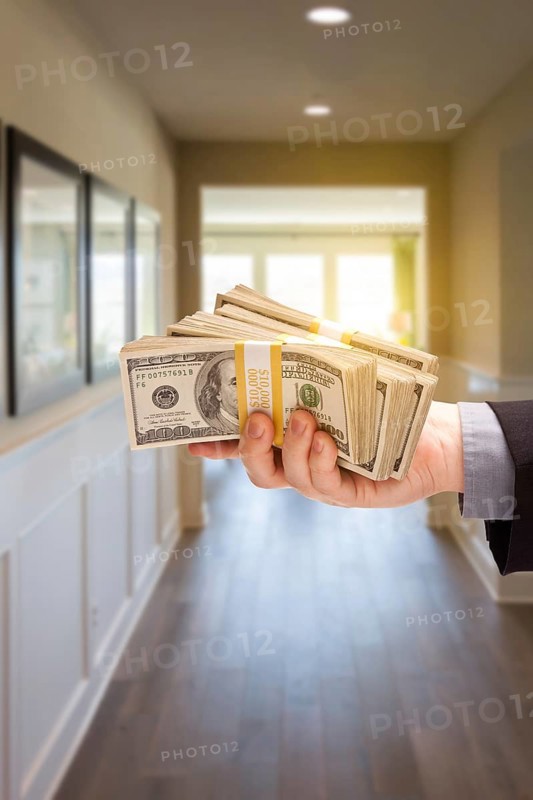 Male hand with stack of cash inside hallway of new house