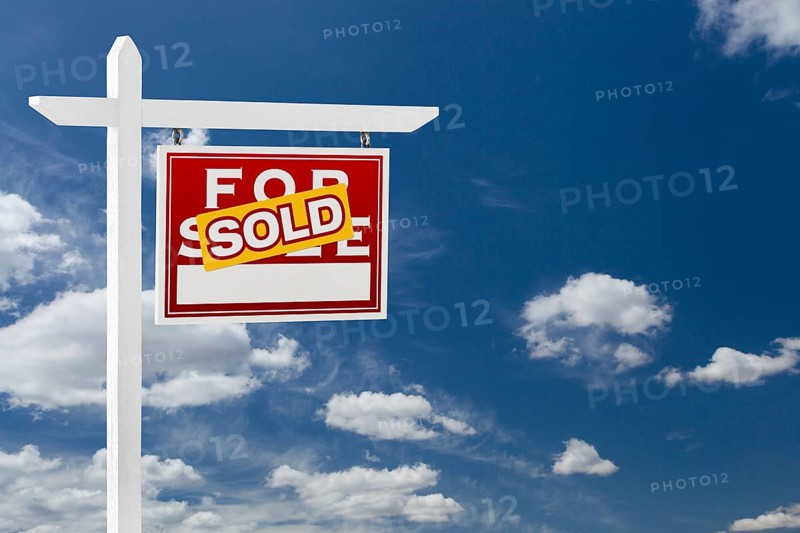 Right facing sold for sale real estate sign over blue sky and clouds with room for your text
