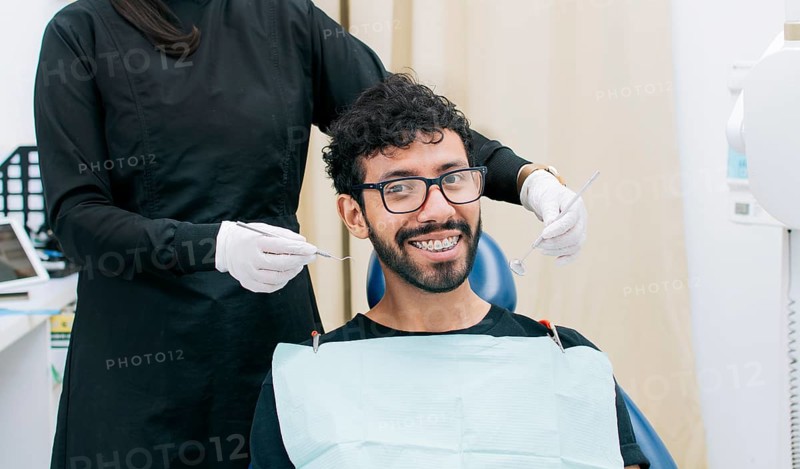 Dentist examining mouth to smiling patient