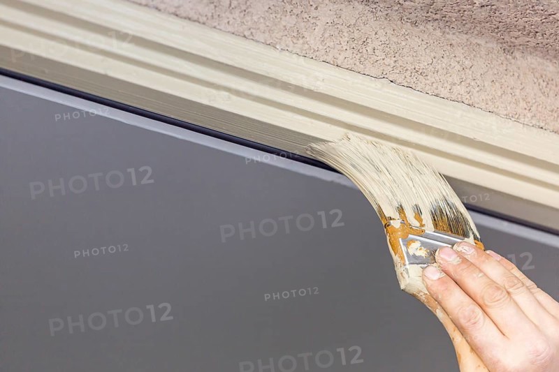 Professional painter cutting in with A brush to paint house door frame