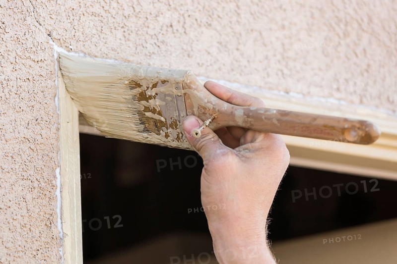 Professional painter cutting in with A brush to paint house door frame