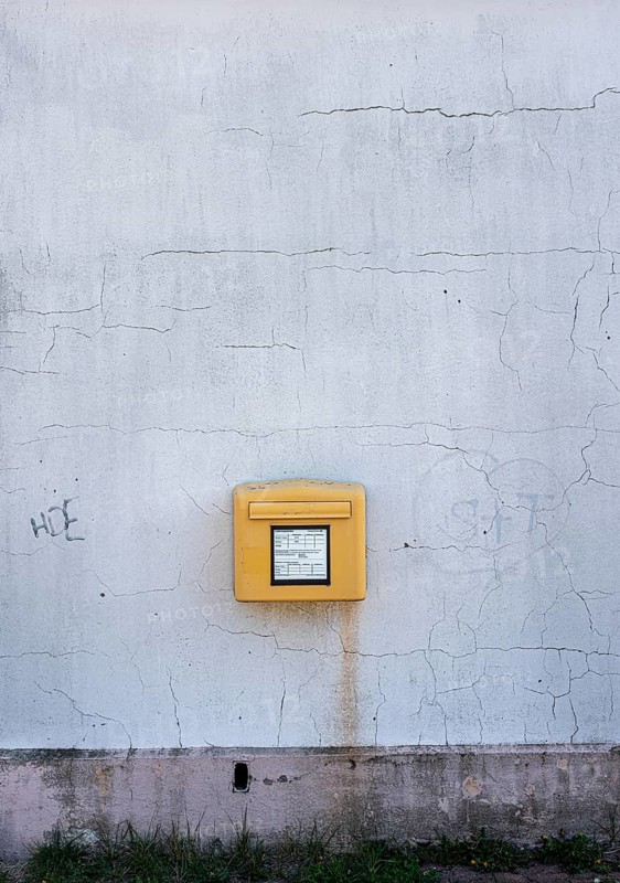 Yellow Deutsche Post letterbox on white wall