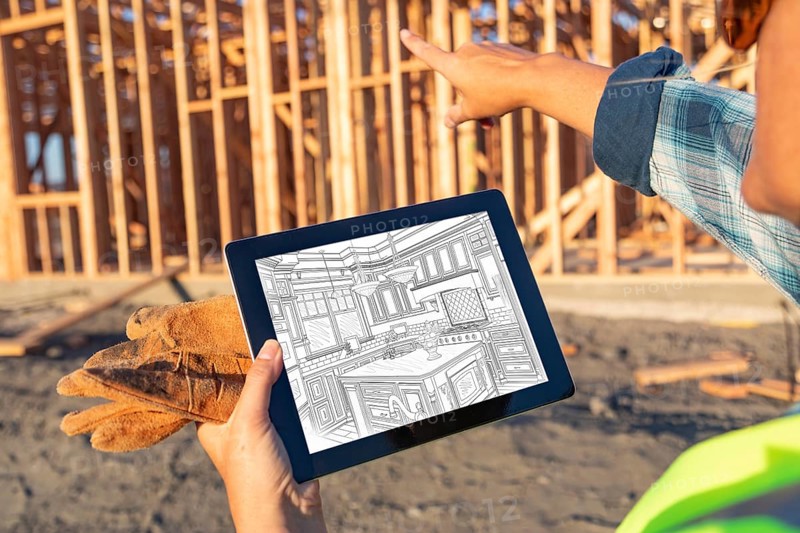 Female construction worker reviewing kitchen drawing on computer pad at construction site