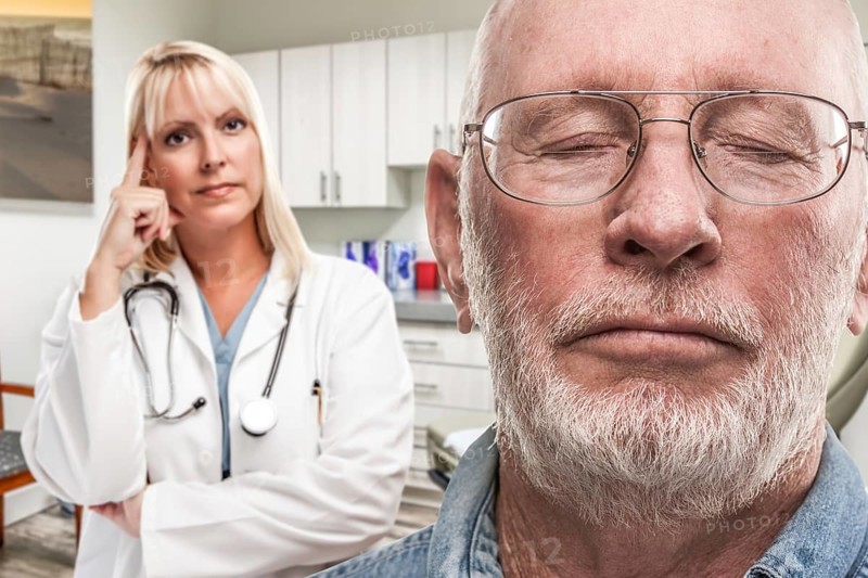 Empathetic doctor standing behind troubled senior adult man in office