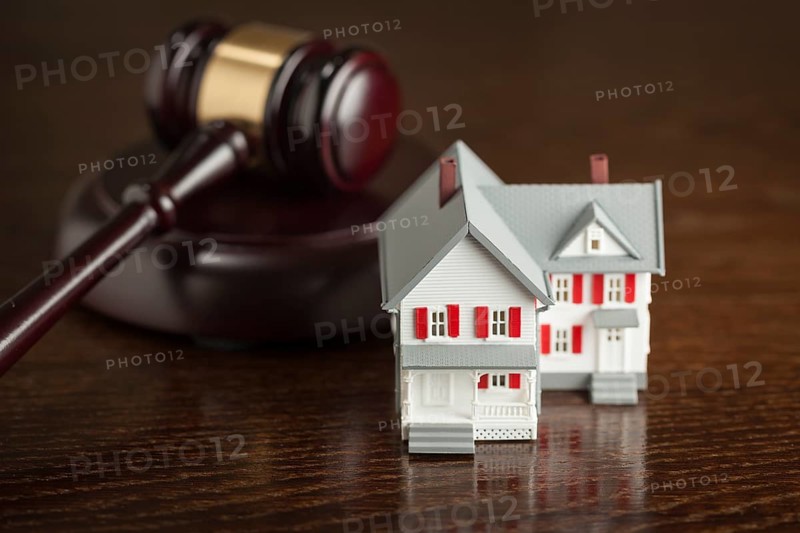 Gavel and small model house on wooden table