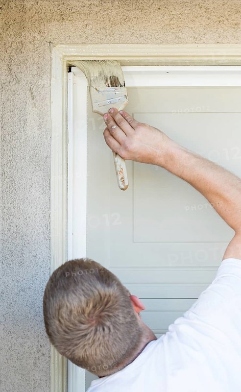 Professional painter cutting in with A brush to paint garage door frame