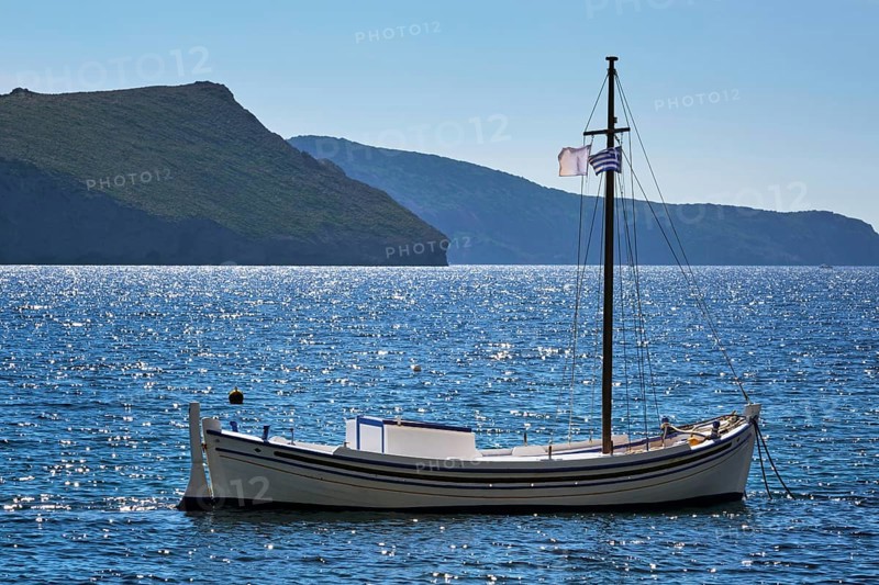 Traditional greek fishing boat in the Aegean sea with greek flag