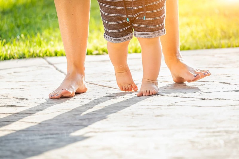 Mother and baby feet taking steps outdoors