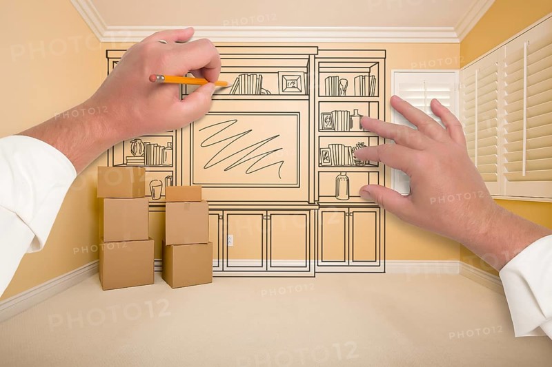 Hands drawing beautiful entertainment unit in room with moving boxes
