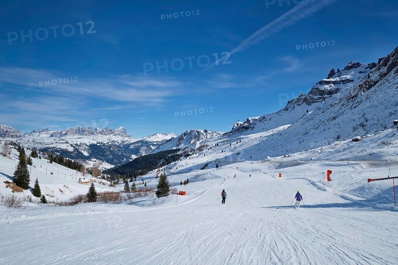 View of a ski resort piste with people skiing in Dolomites in Italy. Canazei