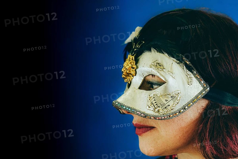 Portrait of a caucasian red head adult woman wearing a venetian theater mask