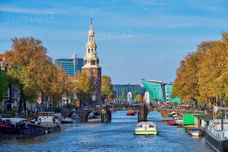 Amterdam cityscape with canal boats and medieval houses and NEMO Science museum and Montelbaanstoren Tower. Amsterdam