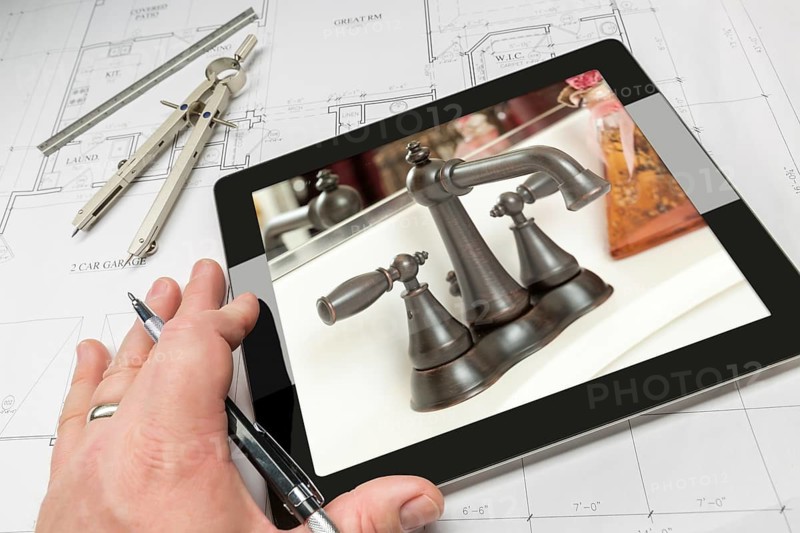 Hand of architect on computer tablet showing luxury bathroom details over house plans