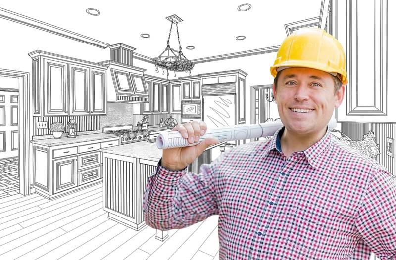 Smiling contractor in hard hat with roll of plans over custom kitchen drawing