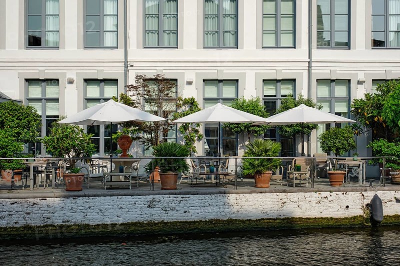Street cafe restaurant tables with tents along canal in Bruges