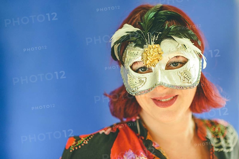 Portrait of a caucasian red head adult woman wearing a venetian theater mask