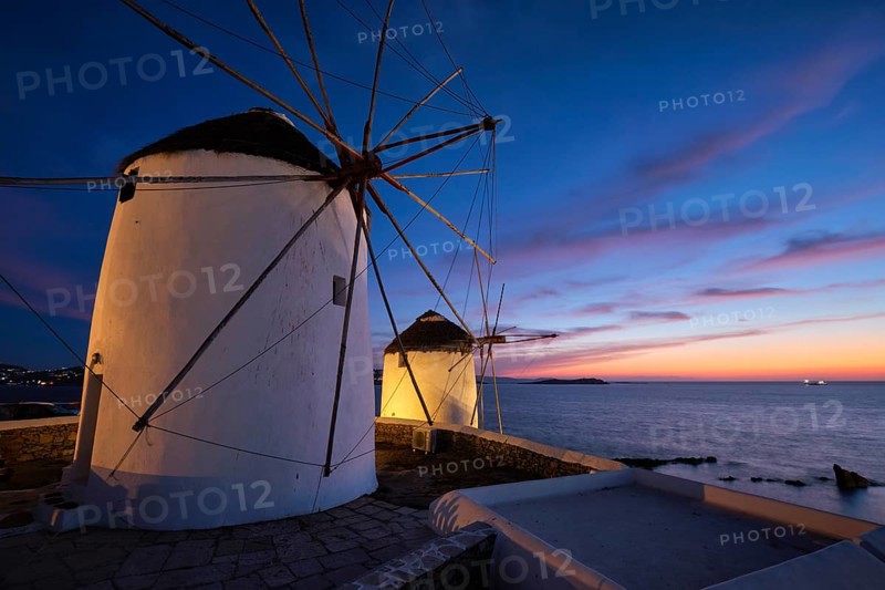 Scenic view of famous Mykonos Chora town windmills. Traditional greek windmills on Mykonos island illuminated in the evening