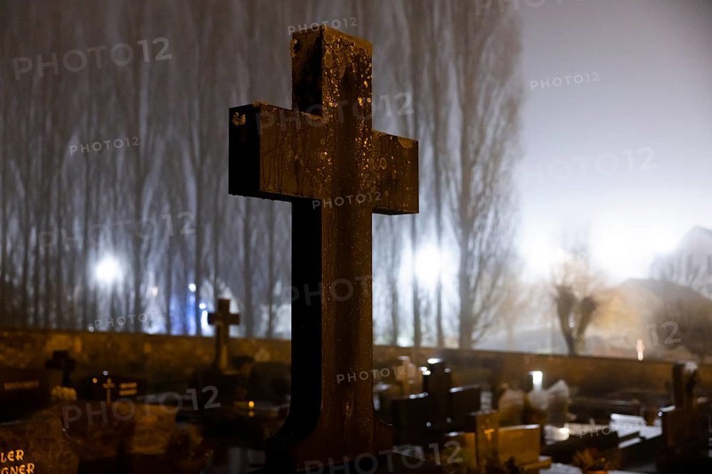 Cross in a cemetery at night with street lighting