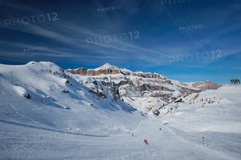 View of a ski resort piste with people skiing in Dolomites in Italy with cable car ski lift. Ski area Arabba. Arabba