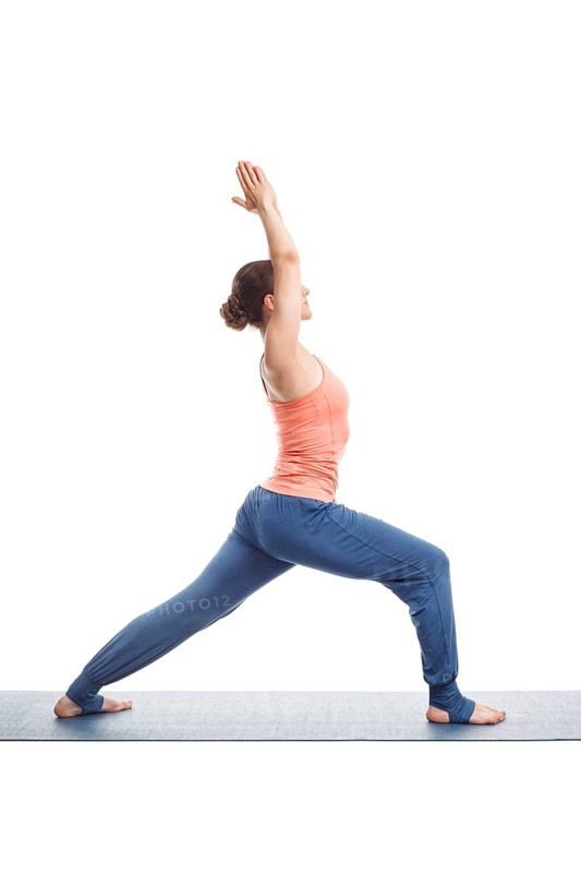 Beautiful sporty fit yogini woman practices yoga asana Virabhadrasana 1