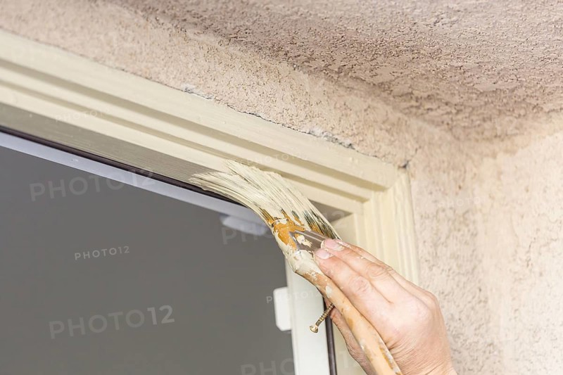 Professional painter cutting in with A brush to paint house door frame
