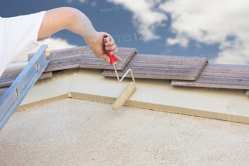 Professional painter using A small roller to paint house fascia