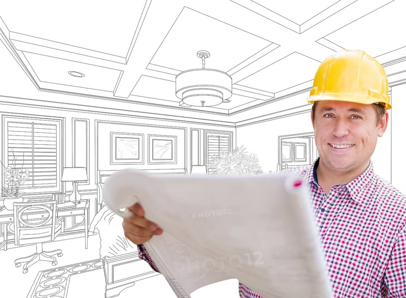 Smiling contractor in hard hat with level over custom bedroom drawing