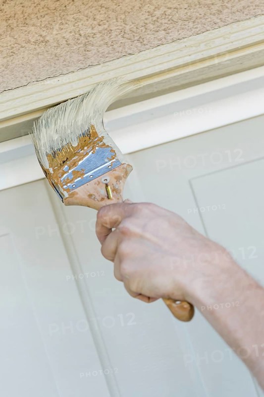 Professional painter cutting in with A brush to paint garage door frame