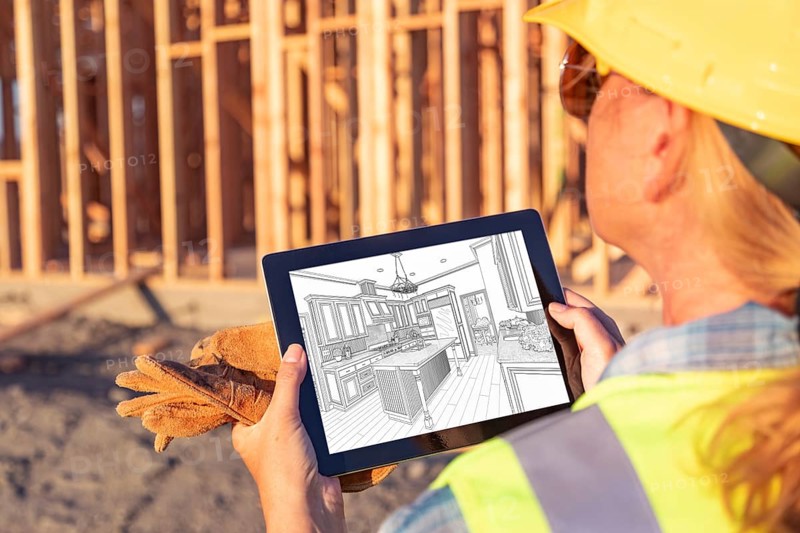 Female construction worker reviewing kitchen drawing on computer pad at construction site