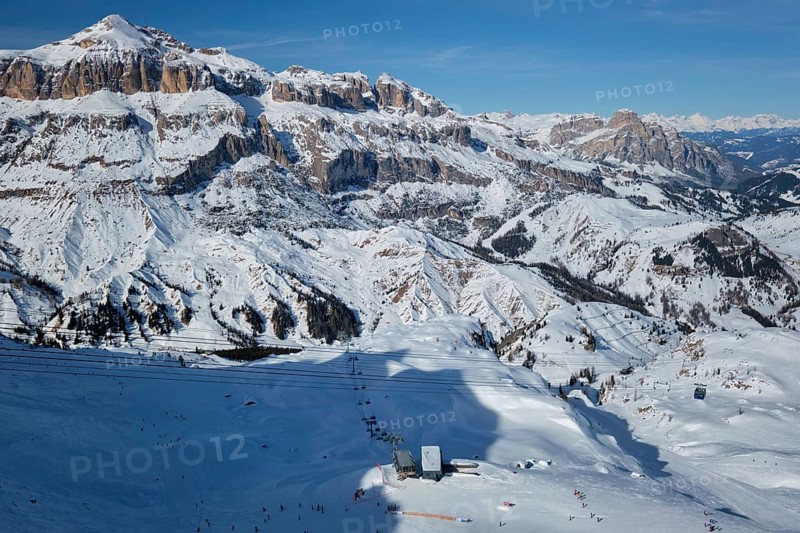 View of a ski resort piste with people skiing in Dolomites in Italy with cable car ski lift Ski area Arabba Arabba