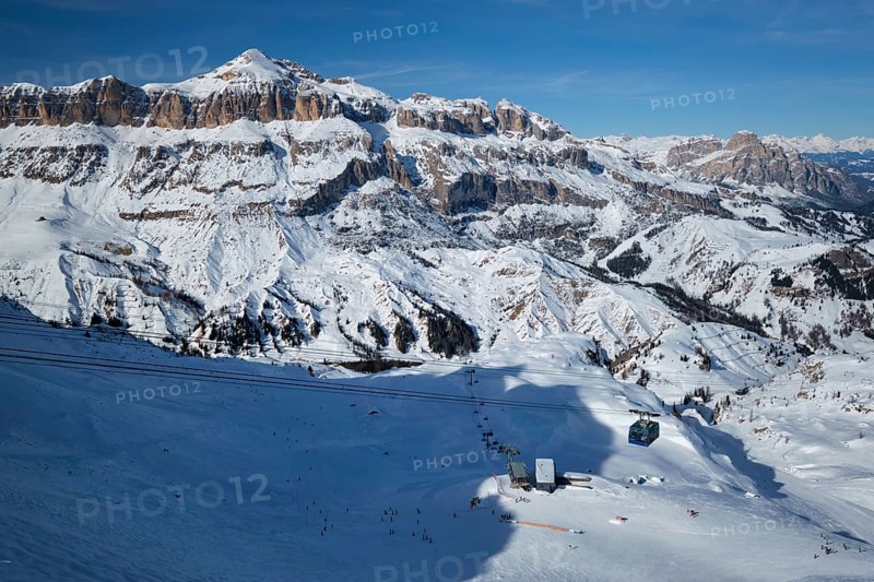 View of a ski resort piste with people skiing in Dolomites in Italy with cable car ski lift. Ski area Arabba. Arabba