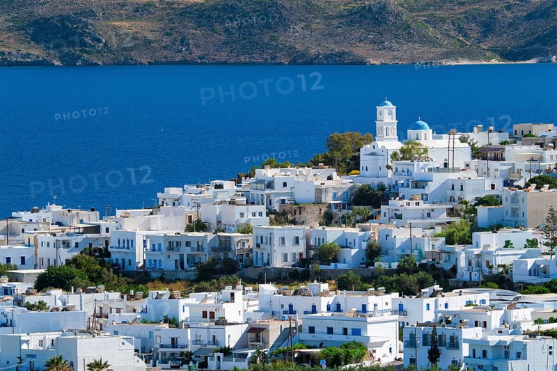 View of Plaka village with traditional Greek church and white painted houses and ocean coast. Milos island