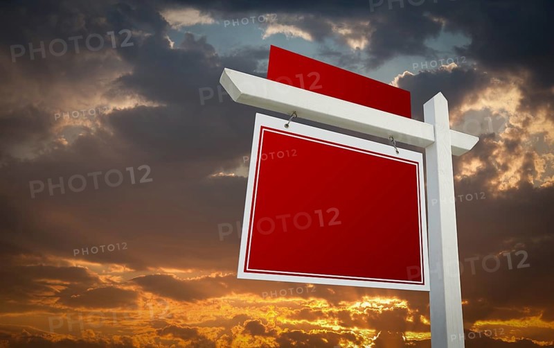 Blank red real estate sign over sunset sky ready for your own message