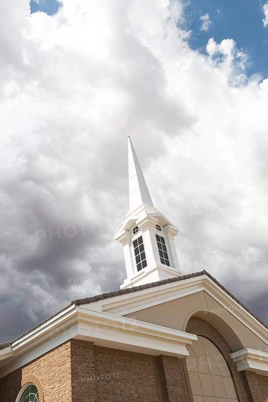 Church steeple tower below ominous stormy thunderstorm clouds