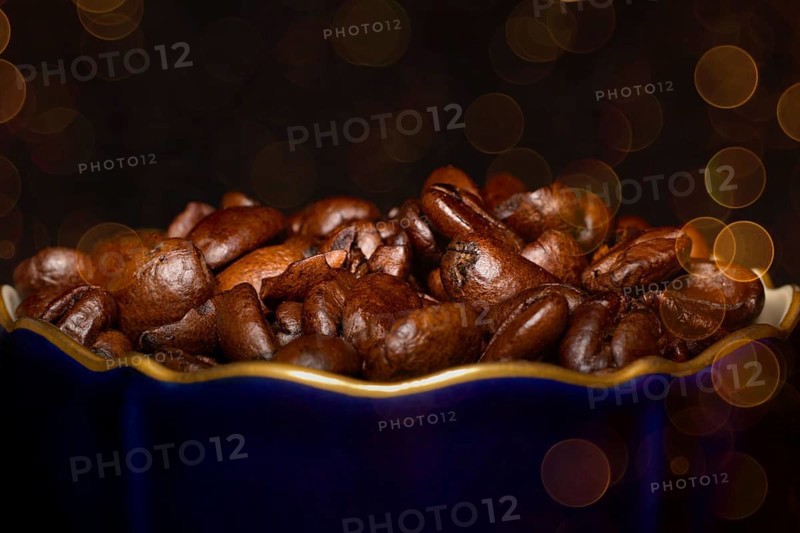 Roasted coffee of the Arabica variety in a porcelain cup in cobalt blue with gold rim