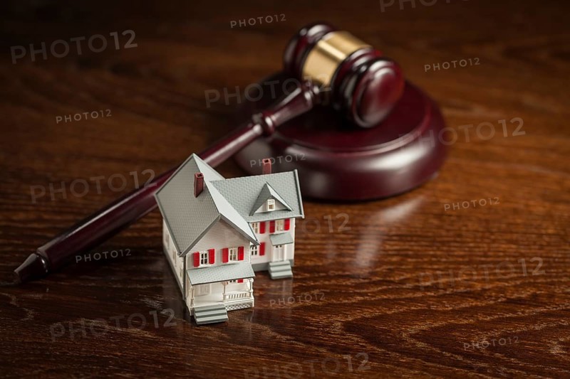 Gavel and small model house on wooden table
