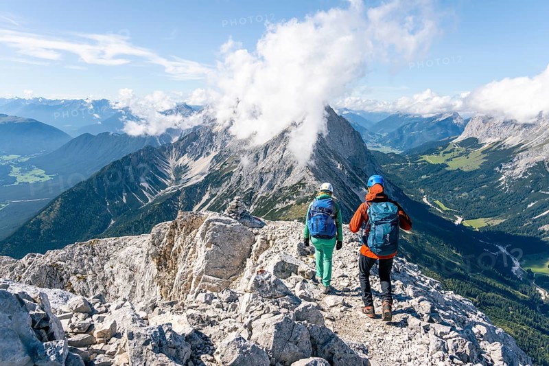 Hiker with climbing helmet on a steep rocky ridge